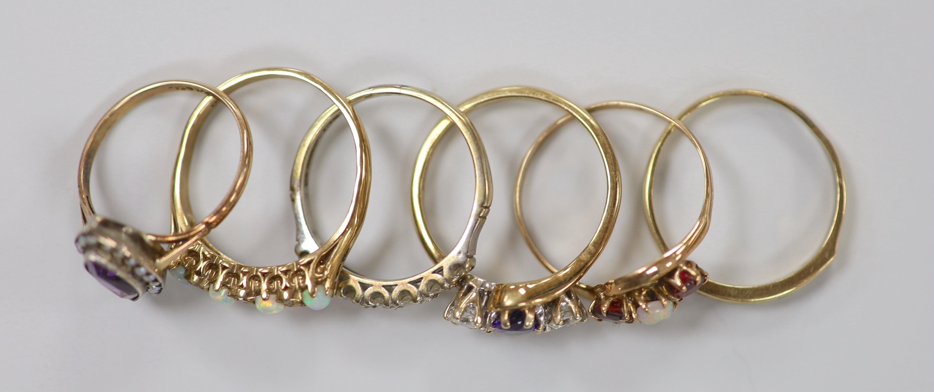 Six assorted modern 9ct and gem set rings, including an amethyst and diamond set three stone crossover ring, size R, white opal and diamond chip and a 9ct and 'sil', amethyst and seed pearl cluster ring, gross weight 15.